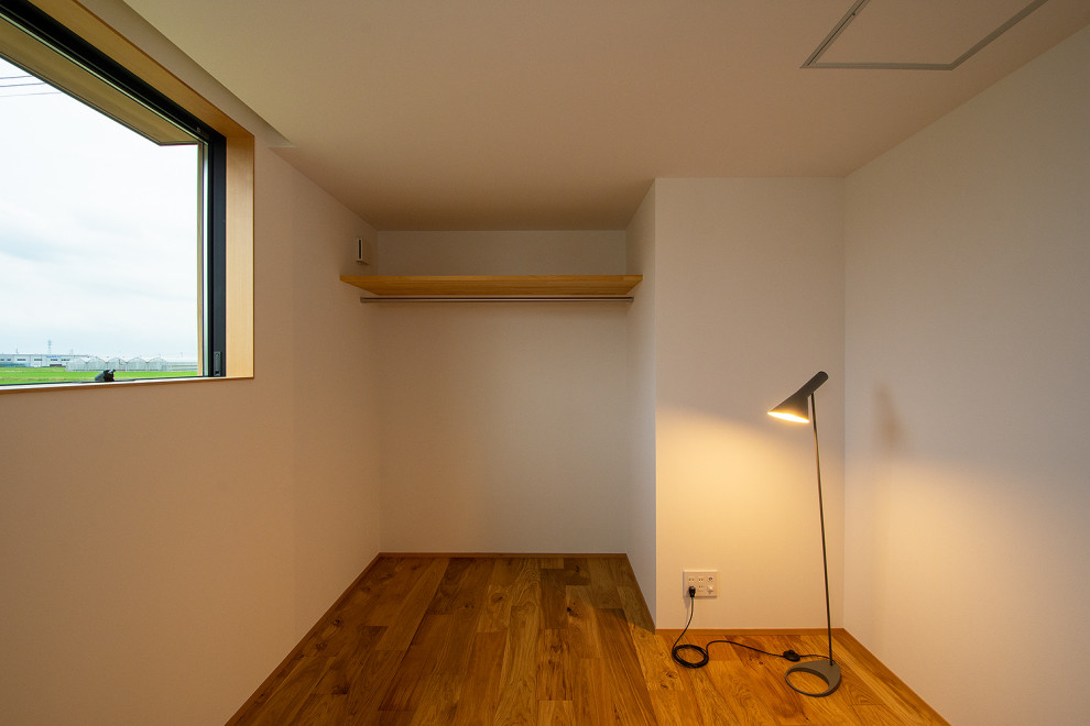 Foto på ett litet könsneutralt småbarnsrum kombinerat med sovrum, med vita väggar och mellanmörkt trägolv