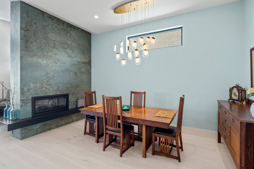Contemporary open plan dining room in Vancouver with blue walls, light hardwood flooring, a ribbon fireplace, a tiled fireplace surround, beige floors and a vaulted ceiling.