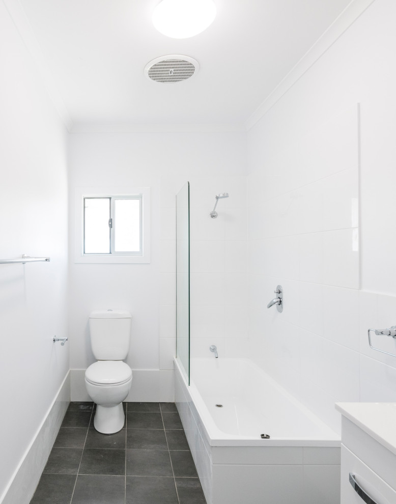 Idées déco pour une petite salle d'eau avec un placard en trompe-l'oeil, des portes de placard blanches, une baignoire d'angle, un combiné douche/baignoire, WC à poser, un carrelage blanc, un mur blanc, un plan de toilette en stratifié, un sol gris, aucune cabine, un plan de toilette blanc, des toilettes cachées, meuble simple vasque, meuble-lavabo sur pied et un plafond en lambris de bois.