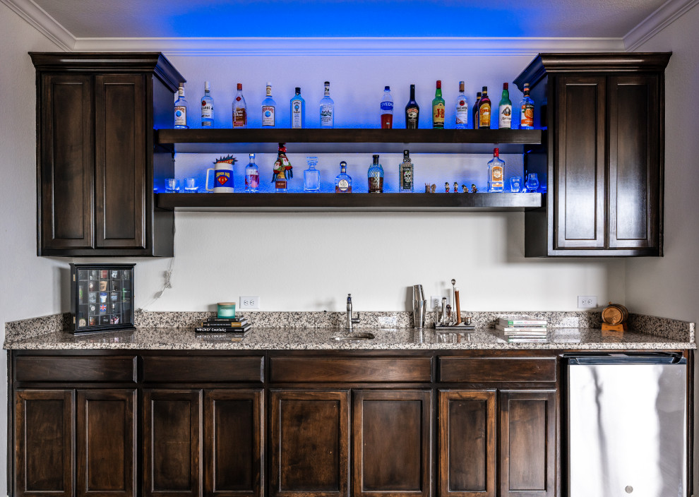 Photo of a classic single-wall wet bar in Dallas with a submerged sink, louvered cabinets, dark wood cabinets, granite worktops, dark hardwood flooring, brown floors and brown worktops.
