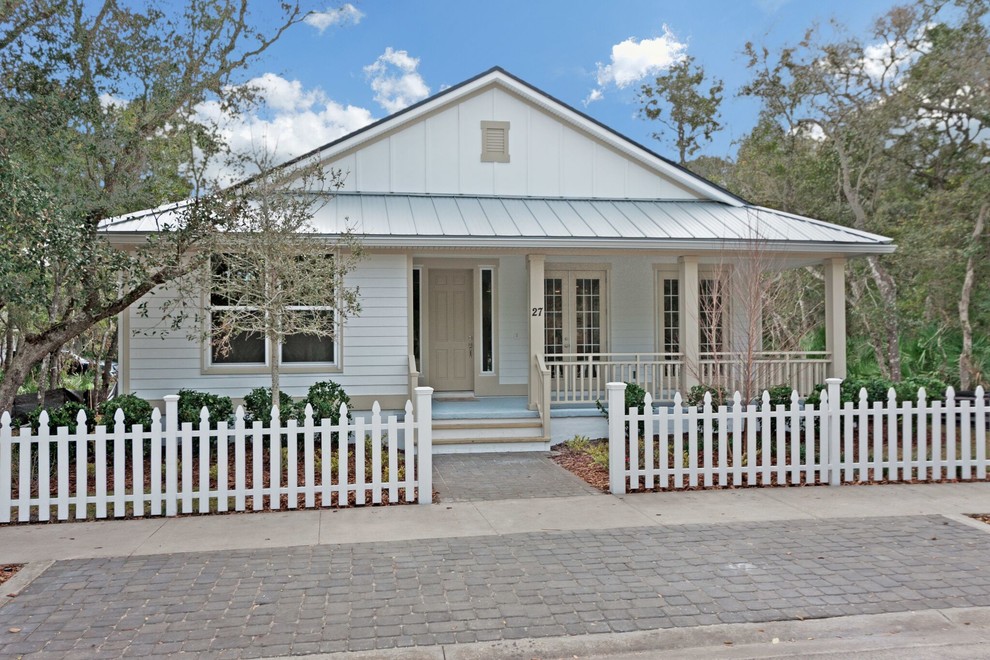 This is an example of a mid-sized beach style one-storey white house exterior in Jacksonville with wood siding, a hip roof and a shingle roof.