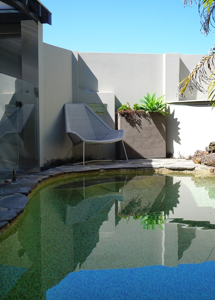 Design ideas for a mid-sized contemporary front yard kidney-shaped pool in Sydney with natural stone pavers.