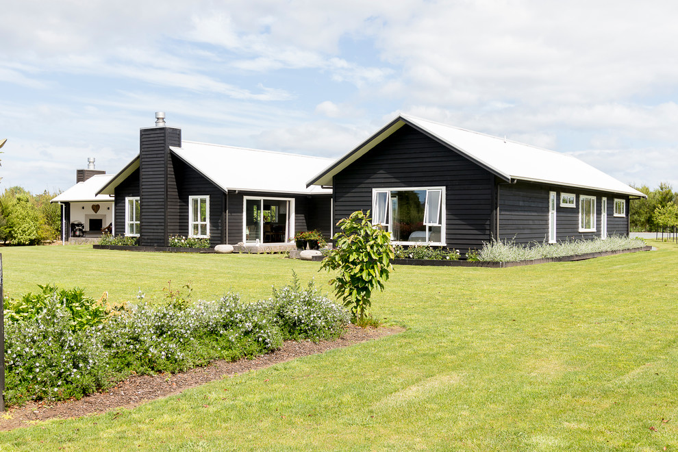 Inspiration for a country one-storey black house exterior in Stockholm with wood siding, a gable roof and a metal roof.