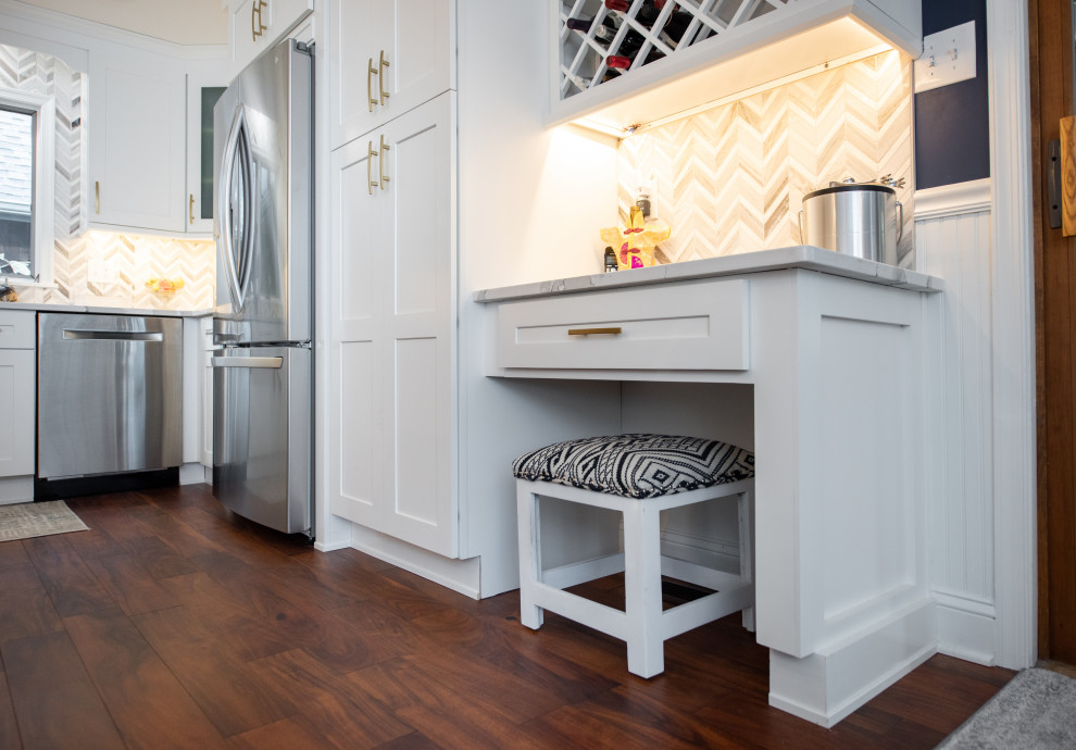 Inredning av ett klassiskt mellanstort vit vitt kök, med en undermonterad diskho, skåp i shakerstil, vita skåp, bänkskiva i kvarts, flerfärgad stänkskydd, stänkskydd i marmor, rostfria vitvaror, mörkt trägolv, en halv köksö och brunt golv