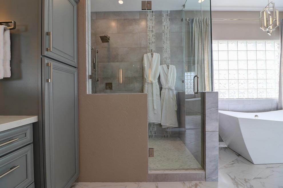 Inspiration for a mid-sized transitional master beige tile and porcelain tile porcelain tile, white floor and double-sink freestanding bathtub remodel in Phoenix with raised-panel cabinets, gray cabinets, a two-piece toilet, beige walls, an undermount sink, quartz countertops, a hinged shower door, white countertops and a built-in vanity