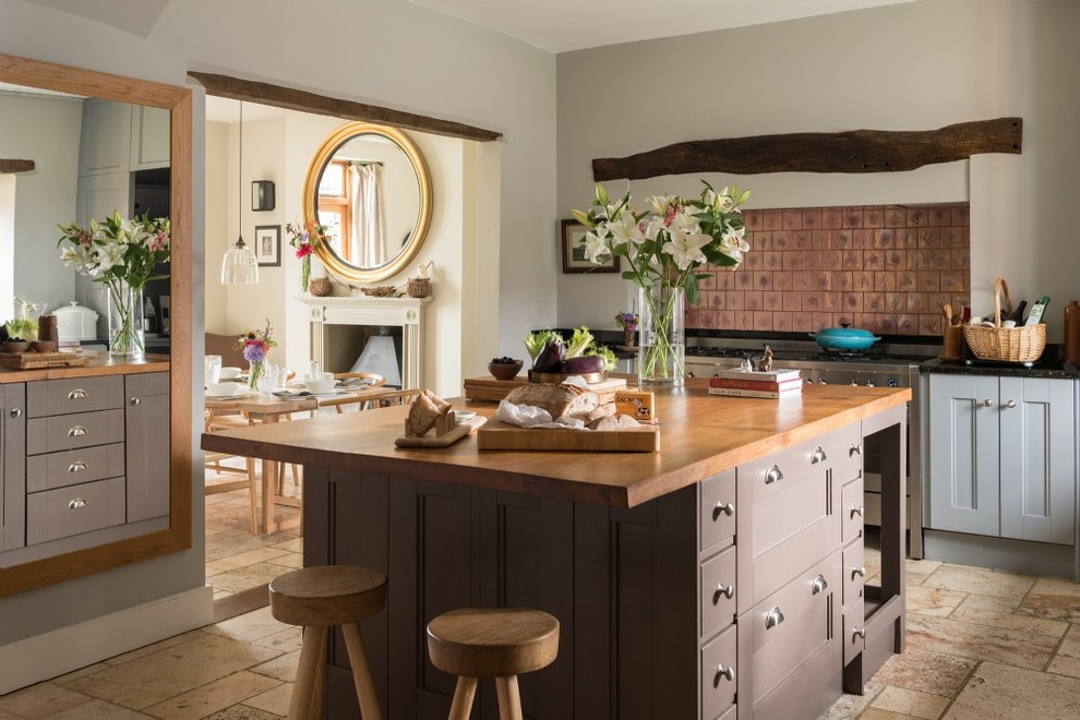 This is an example of a mid-sized country l-shaped open plan kitchen in Other with brown cabinets, wood benchtops, with island, beige floor, black benchtop, recessed-panel cabinets, metallic splashback, metal splashback and stainless steel appliances.