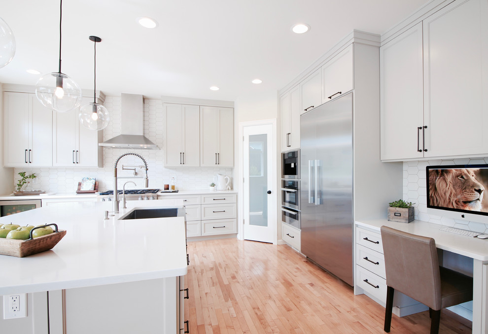 Eat-in kitchen - large transitional l-shaped light wood floor eat-in kitchen idea in Seattle with a farmhouse sink, shaker cabinets, gray cabinets, quartz countertops, white backsplash, porcelain backsplash, stainless steel appliances and an island