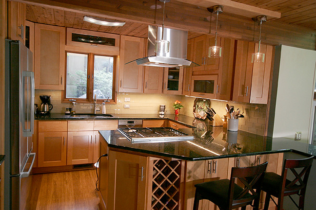 Eat-in kitchen - small transitional l-shaped porcelain tile eat-in kitchen idea with shaker cabinets, light wood cabinets, granite countertops, beige backsplash, glass tile backsplash, stainless steel appliances and a peninsula