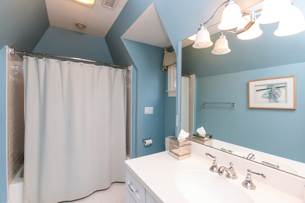 This is an example of a mid-sized traditional 3/4 bathroom in Boston with recessed-panel cabinets, white cabinets, a shower/bathtub combo, a two-piece toilet, blue tile, beige walls, an integrated sink and solid surface benchtops.