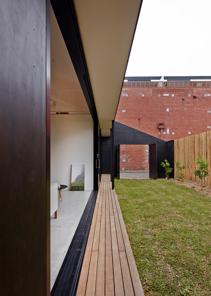 This is an example of a contemporary two-storey black exterior in Melbourne with wood siding.