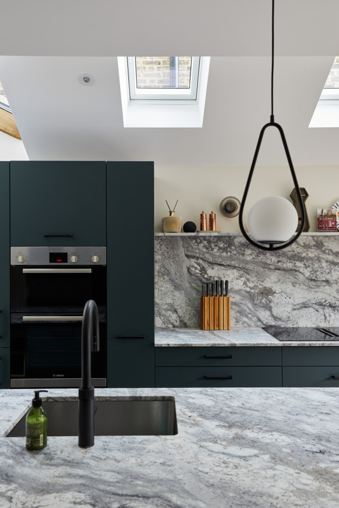 Mid-sized modern galley open plan kitchen in London with an undermount sink, flat-panel cabinets, green cabinets, quartz benchtops, engineered quartz splashback, black appliances and with island.