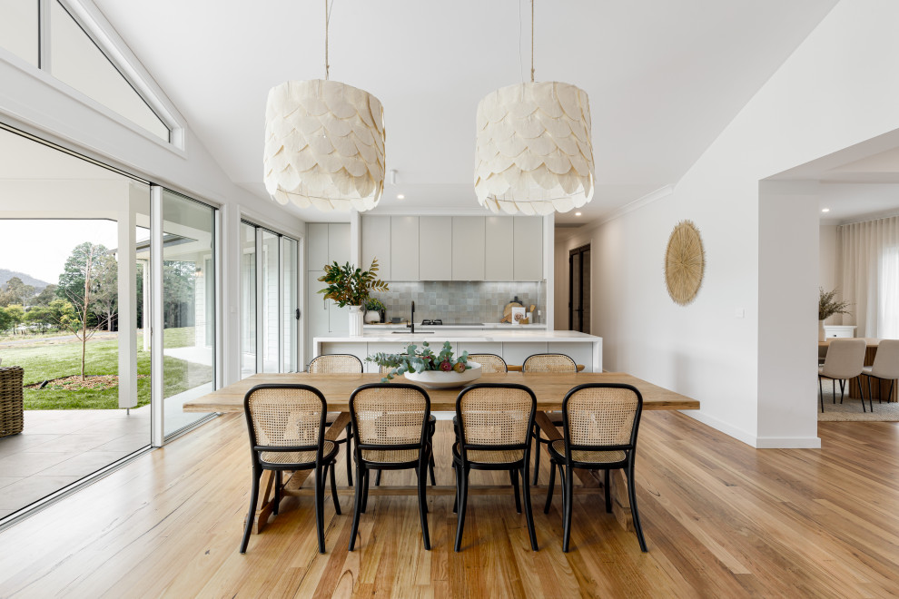 Design ideas for a large contemporary open plan dining room in Wollongong with white walls, light hardwood flooring, a two-sided fireplace, a timber clad chimney breast and all types of wall treatment.
