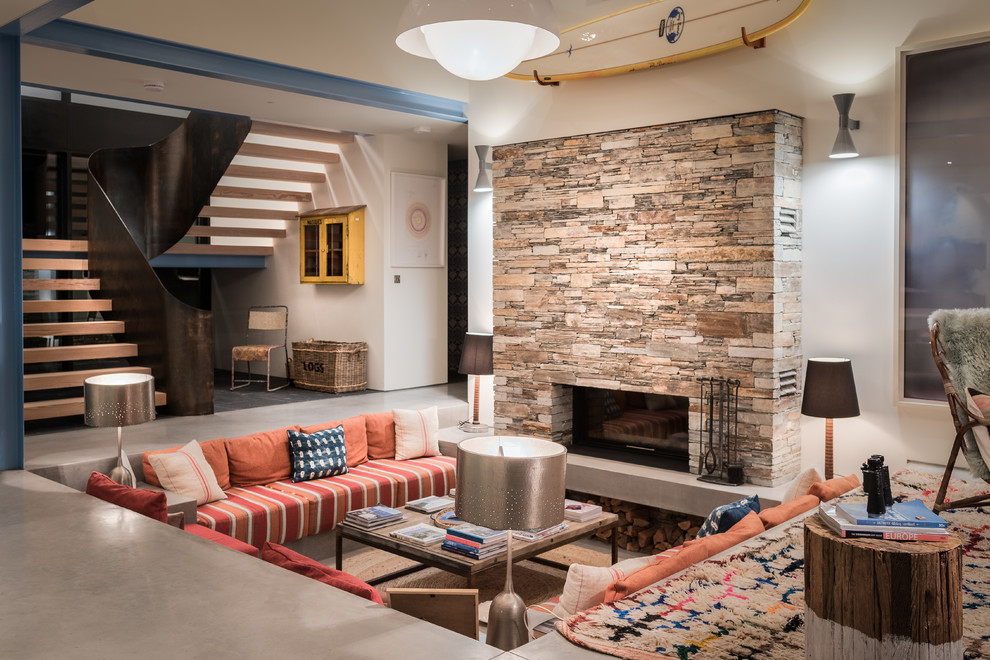 Inspiration for a large contemporary open concept living room in Cornwall with concrete floors, a stone fireplace surround, grey floor, white walls and a standard fireplace.