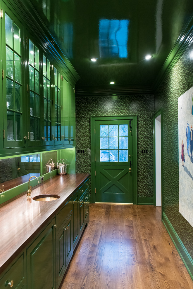 This is an example of a large traditional galley wet bar in Philadelphia with an undermount sink, raised-panel cabinets, green cabinets, wood benchtops, mirror splashback, medium hardwood floors, brown floor and brown benchtop.