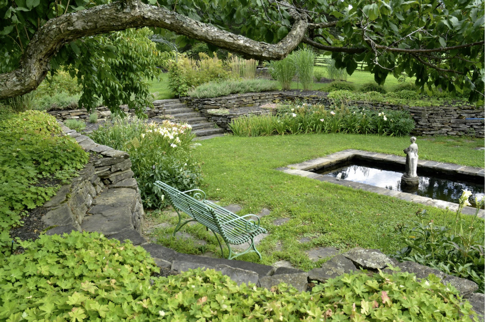 Design ideas for a traditional partial sun garden in Montreal with with pond and a stone fence.
