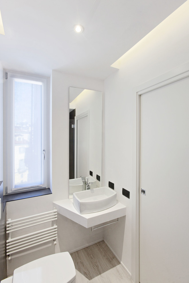 Design ideas for a powder room in Milan with light hardwood floors.