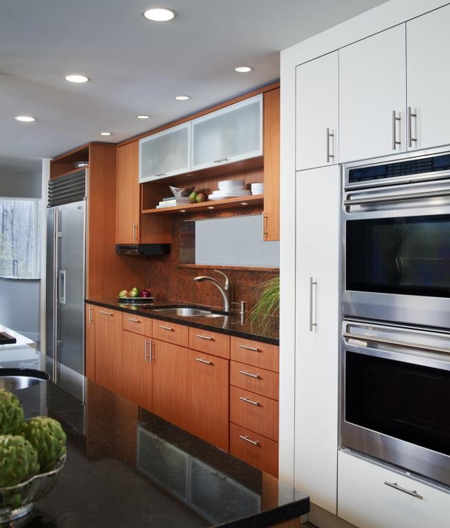 This is an example of an expansive modern u-shaped eat-in kitchen in DC Metro with an undermount sink, flat-panel cabinets, medium wood cabinets, granite benchtops, brown splashback, stone slab splashback, stainless steel appliances, slate floors and with island.