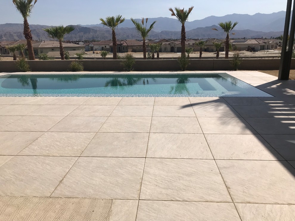 Design ideas for a large modern backyard rectangular infinity pool in Other with tile.