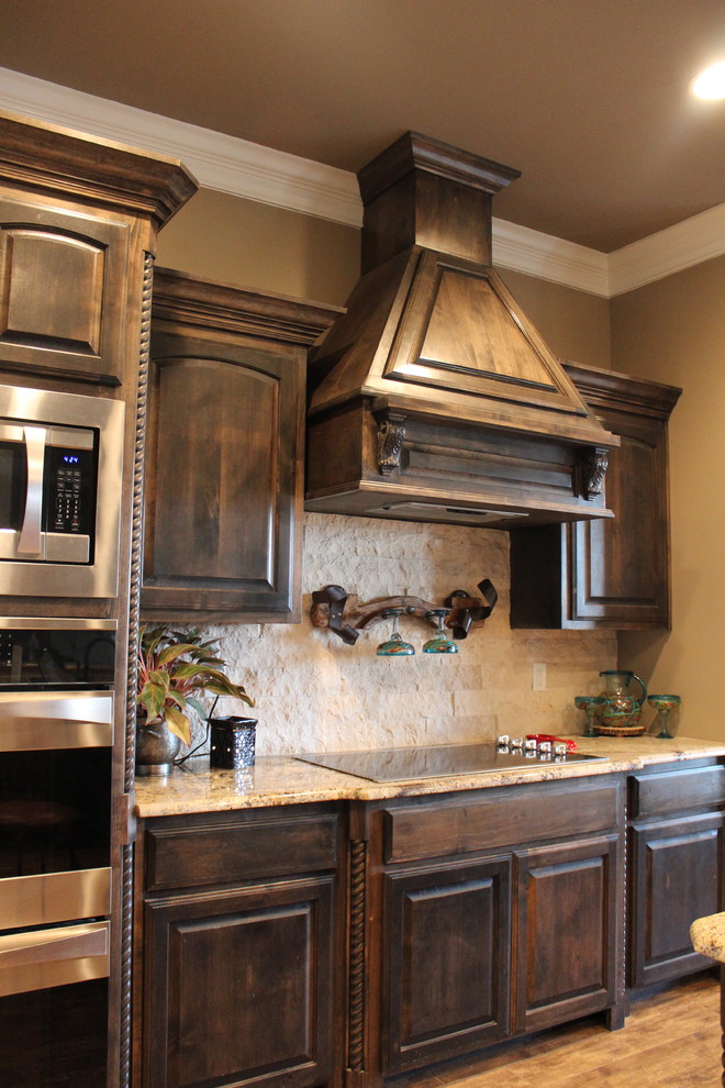 Inspiration for a mid-sized rustic ceramic tile eat-in kitchen remodel in Austin with a drop-in sink, raised-panel cabinets, dark wood cabinets, granite countertops, beige backsplash, stone tile backsplash, stainless steel appliances and an island