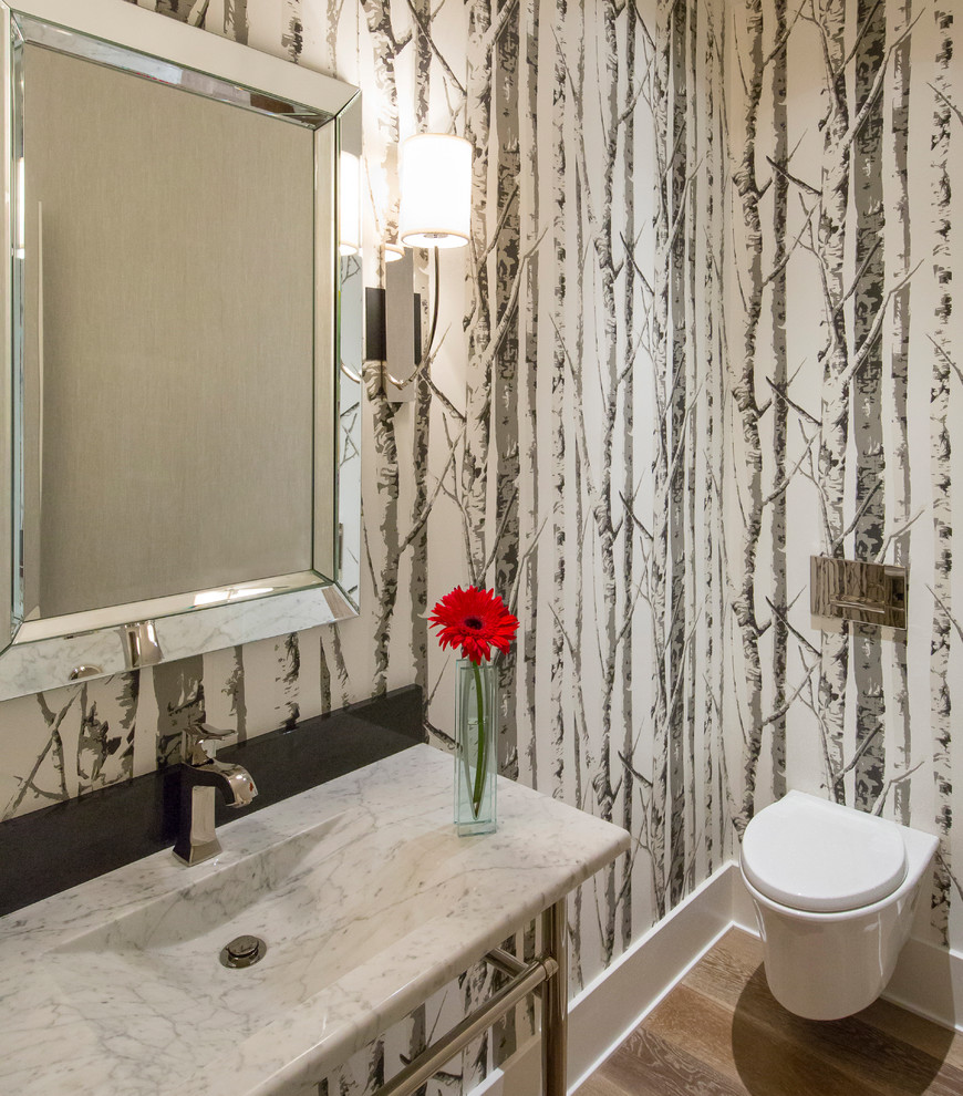 Inspiration for a transitional powder room in Denver with a wall-mount toilet, black and white tile, stone slab, black walls, light hardwood floors, an integrated sink, marble benchtops and beige floor.