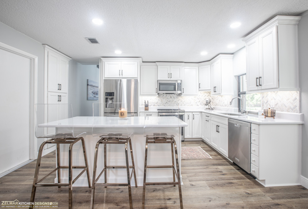Mid-sized scandinavian l-shaped eat-in kitchen in Orlando with a single-bowl sink, recessed-panel cabinets, white cabinets, quartz benchtops, multi-coloured splashback, ceramic splashback, vinyl floors, with island, brown floor and white benchtop.