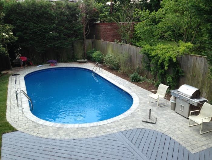 Photo of a large traditional backyard round natural pool in Baltimore with a water feature and natural stone pavers.