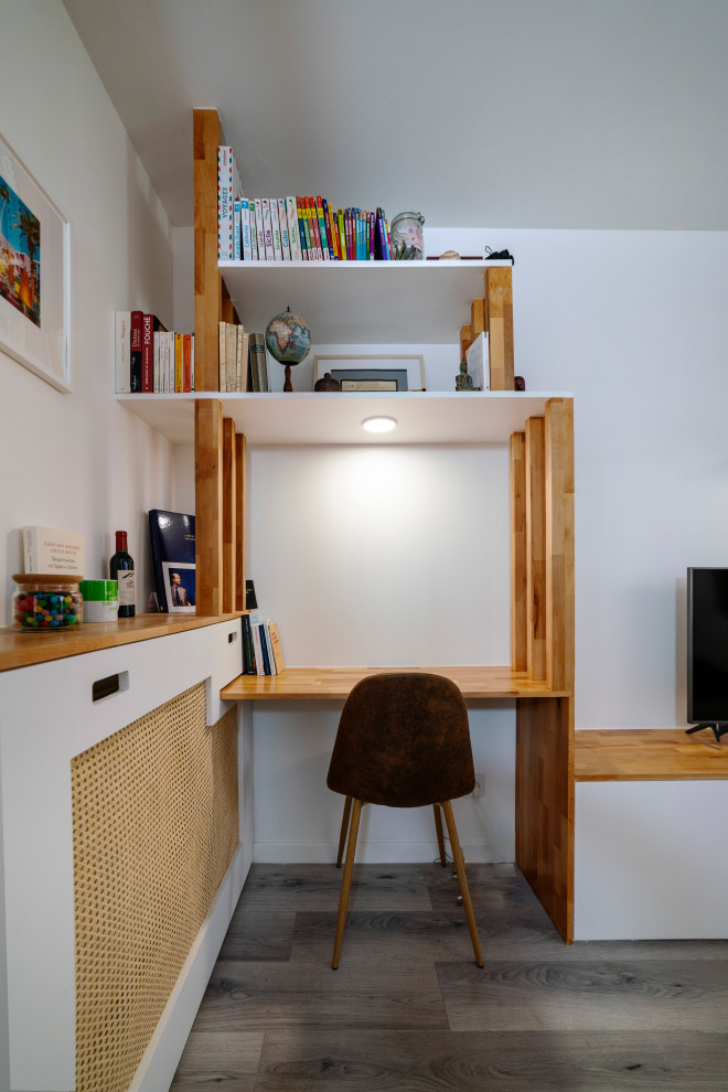 Réalisation d'un bureau nordique de taille moyenne avec une bibliothèque ou un coin lecture, un mur blanc, parquet clair, aucune cheminée, un bureau intégré et un sol beige.