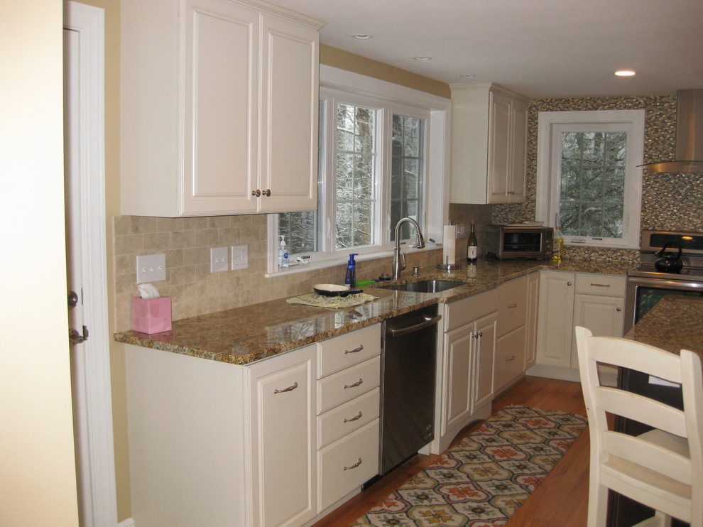 Inspiration for a transitional l-shaped light wood floor eat-in kitchen remodel in Boston with an undermount sink, raised-panel cabinets, white cabinets, granite countertops, beige backsplash, ceramic backsplash, stainless steel appliances and an island