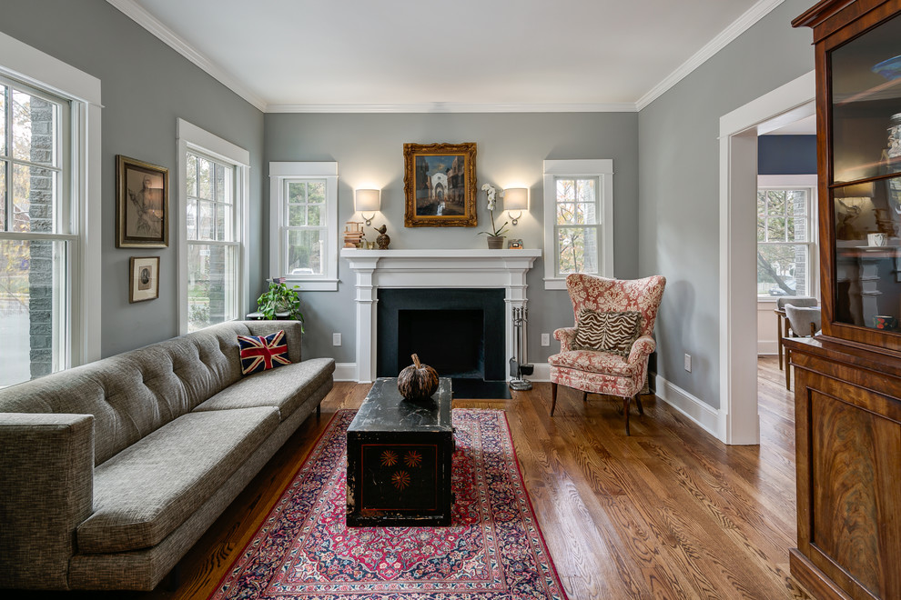 Inspiration for a mid-sized traditional formal enclosed living room in Orange County with grey walls, medium hardwood floors, a standard fireplace, a plaster fireplace surround and no tv.