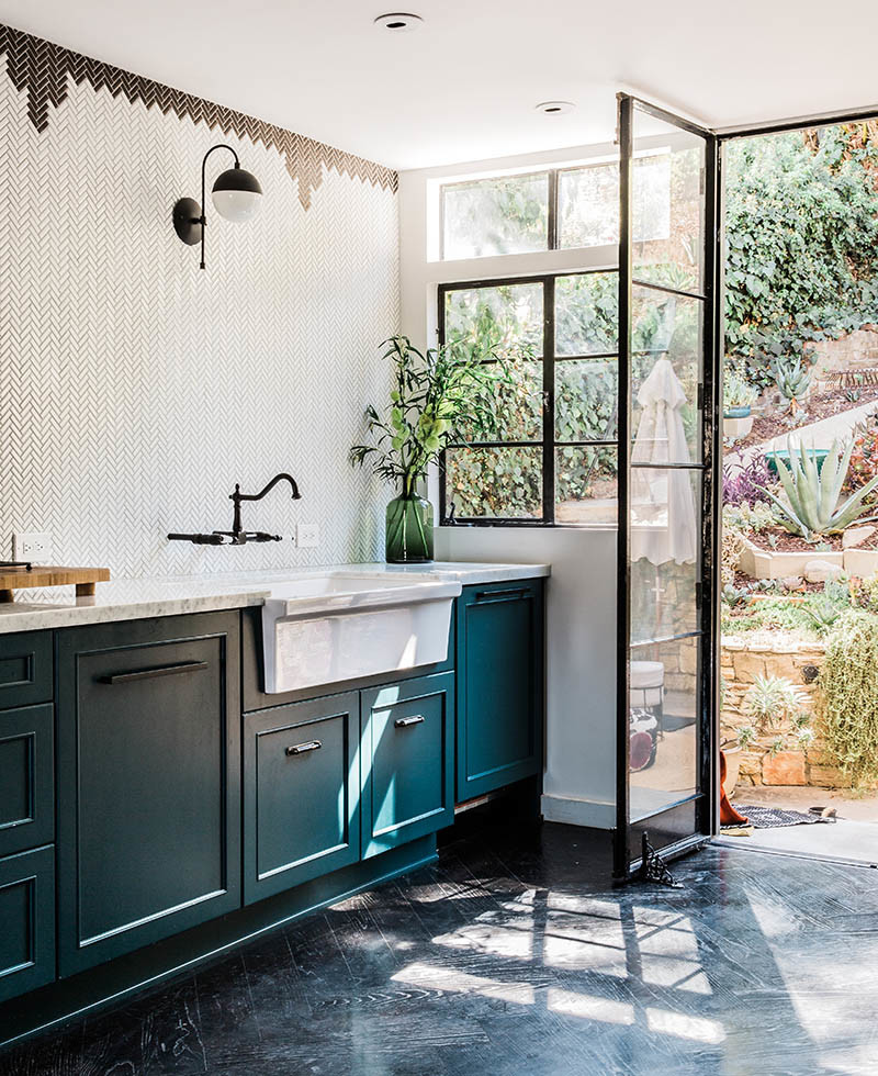 Photo of a small eclectic galley separate kitchen in San Francisco with a farmhouse sink, flat-panel cabinets, blue cabinets, marble benchtops, white splashback, ceramic splashback, panelled appliances, dark hardwood floors and white benchtop.