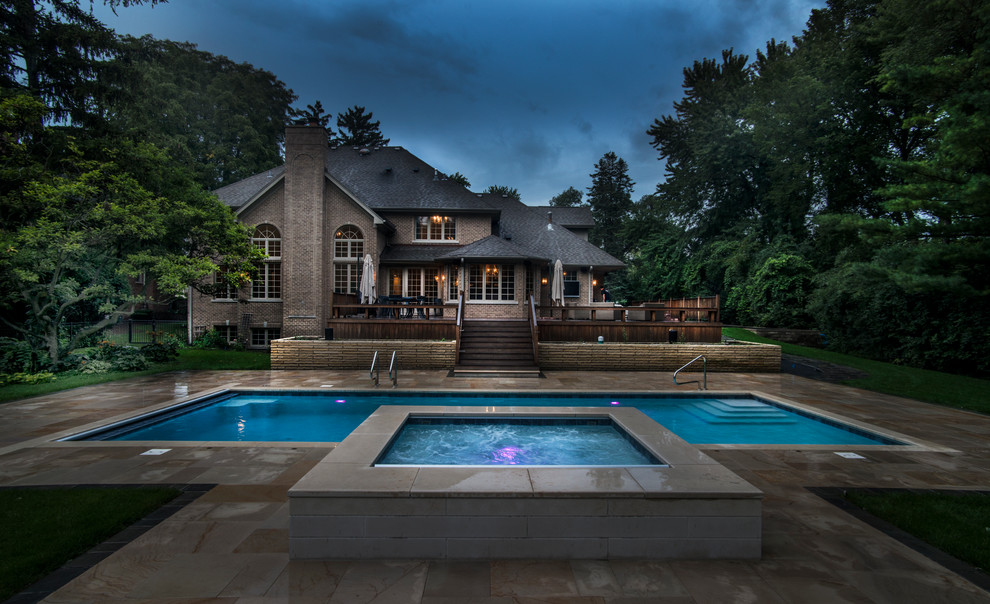 This is an example of a mid-sized traditional backyard rectangular lap pool in Chicago with a hot tub and concrete pavers.