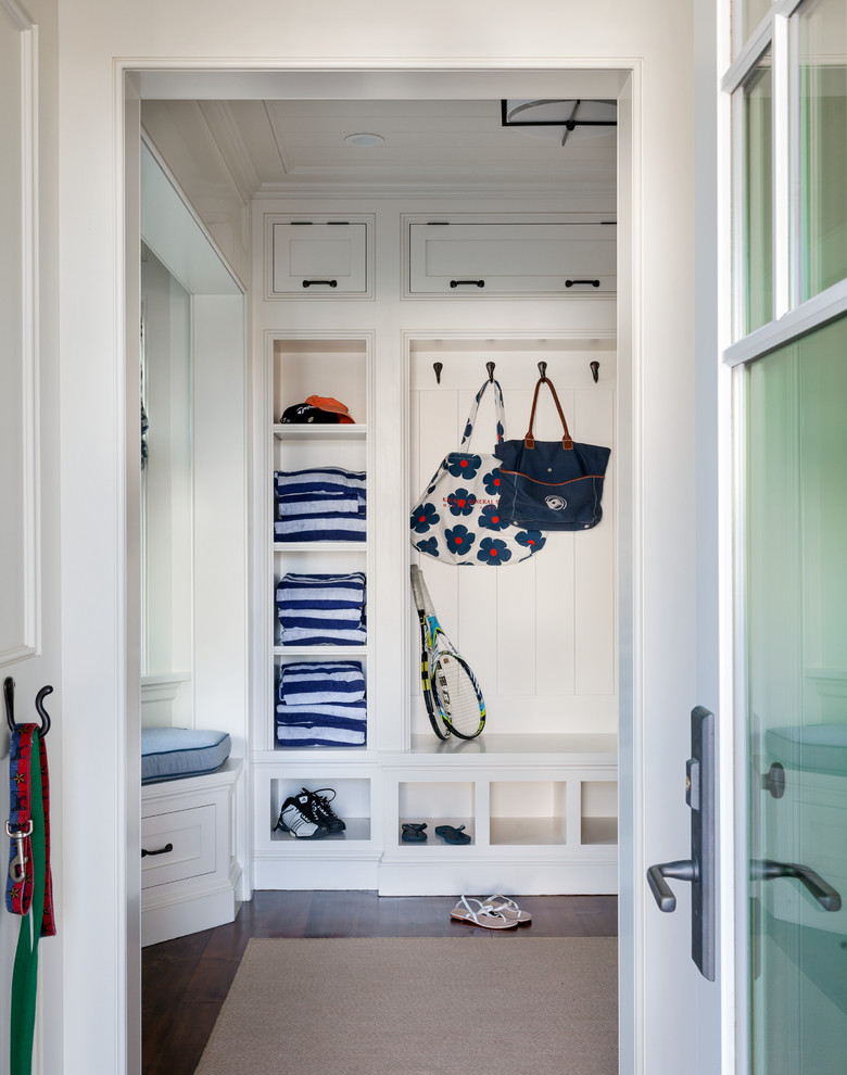 This is an example of a large beach style mudroom in Boston with white walls, dark hardwood floors and a white front door.
