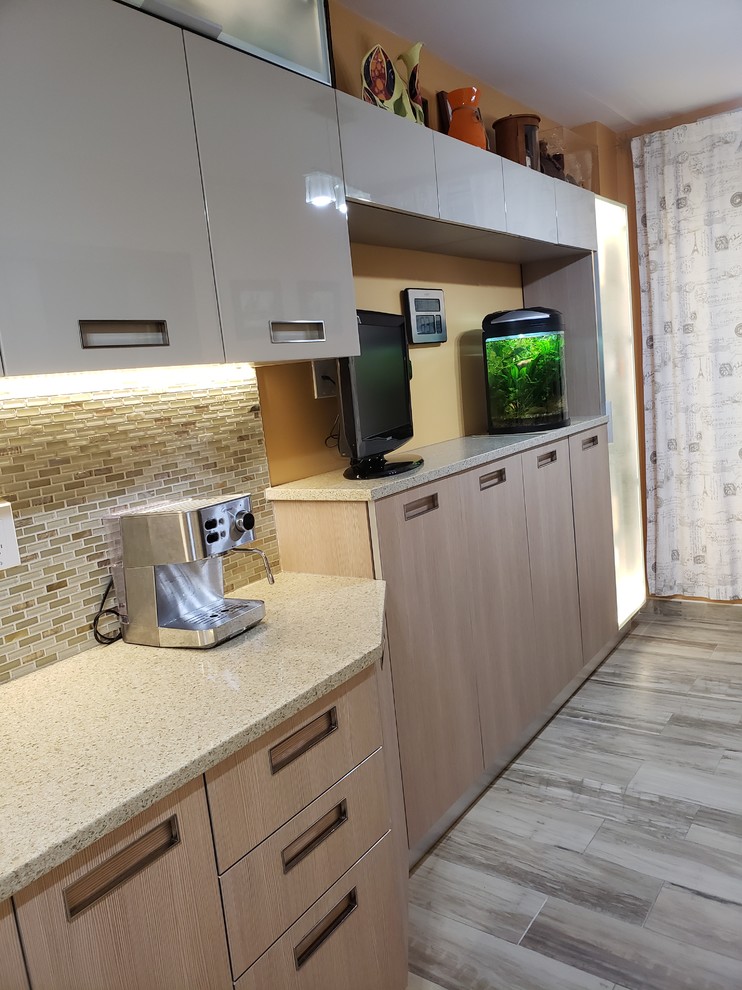 Photo of a mid-sized modern galley eat-in kitchen in New York with an undermount sink, flat-panel cabinets, beige cabinets, quartz benchtops, multi-coloured splashback, glass tile splashback, stainless steel appliances, porcelain floors and beige benchtop.