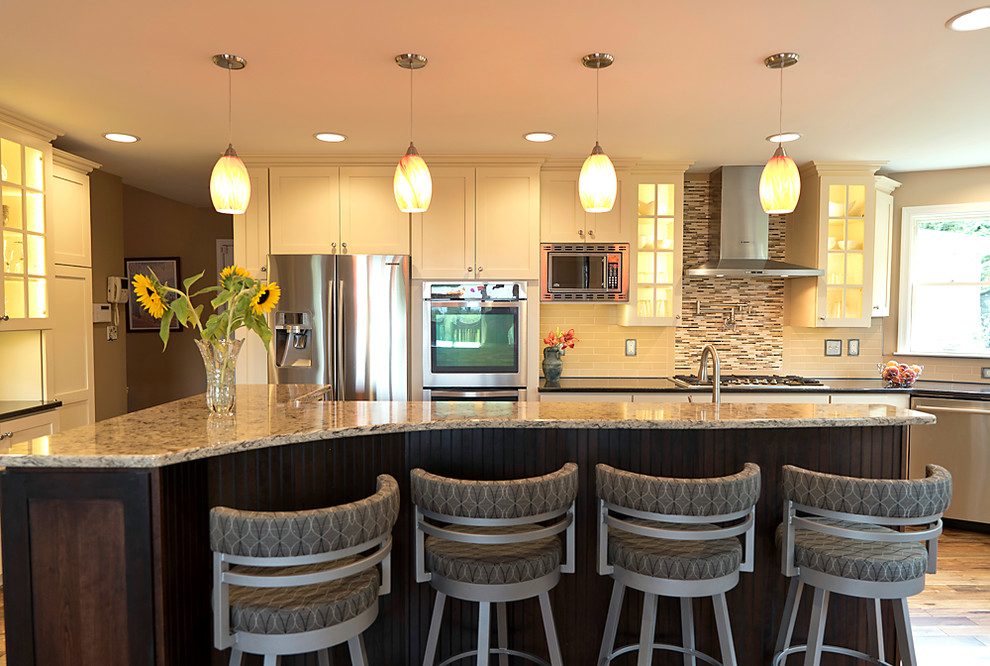 Open concept kitchen - eclectic l-shaped medium tone wood floor open concept kitchen idea in Baltimore with a double-bowl sink, shaker cabinets, white cabinets, solid surface countertops, gray backsplash, subway tile backsplash, stainless steel appliances and an island