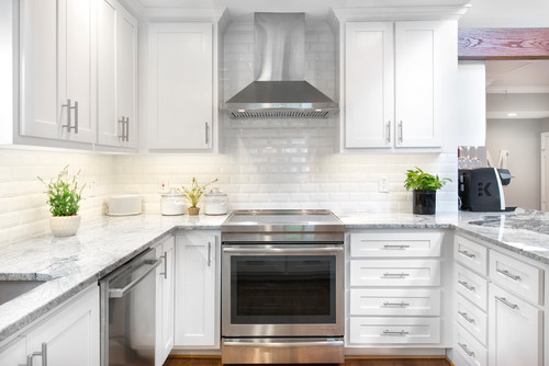 Modern U-shaped kitchen with white shaker RTA cabinets, stainless steel range and hood, subway-tile backsplash, and gray quartz countertops.