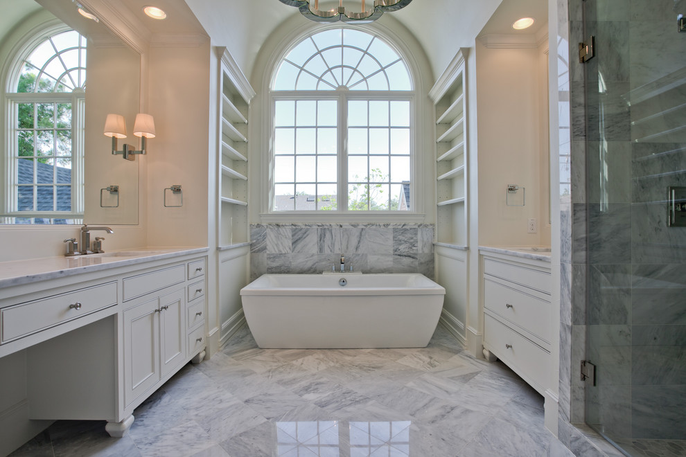 Design ideas for a large traditional master bathroom in Dallas with beaded inset cabinets, white cabinets, a freestanding tub, white tile, an alcove shower, marble, beige walls, marble floors, an undermount sink, marble benchtops, grey floor and a hinged shower door.