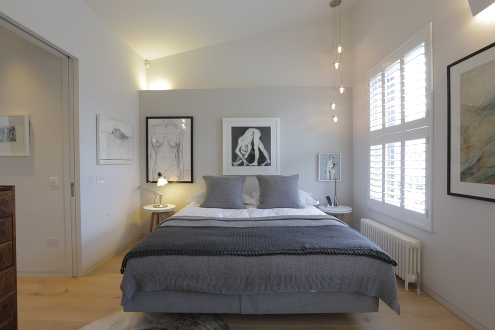 Mid-sized contemporary master bedroom in London with white walls, light hardwood floors, beige floor and no fireplace.