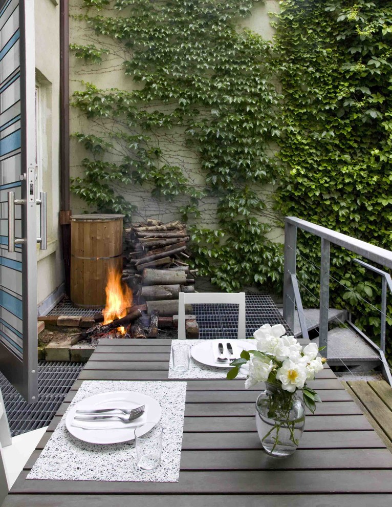 Photo of a small contemporary backyard deck in New York with no cover and a fire feature.