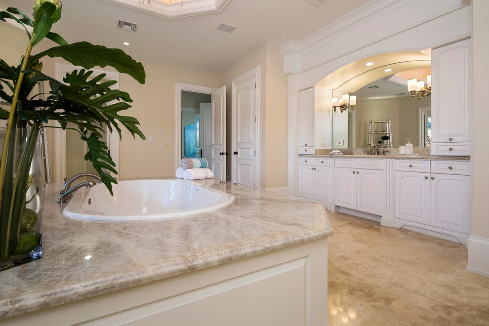 Inspiration for an expansive mediterranean master bathroom in Miami with raised-panel cabinets, white cabinets, a drop-in tub, marble floors, marble benchtops and beige floor.