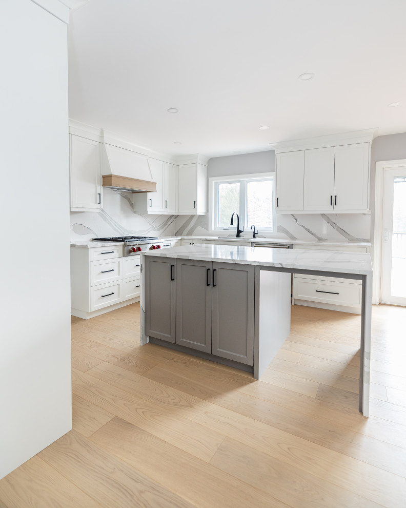 Eat-in kitchen - mid-sized transitional u-shaped light wood floor eat-in kitchen idea in Toronto with an undermount sink, shaker cabinets, white cabinets, quartz countertops, white backsplash, quartz backsplash, stainless steel appliances, an island and white countertops