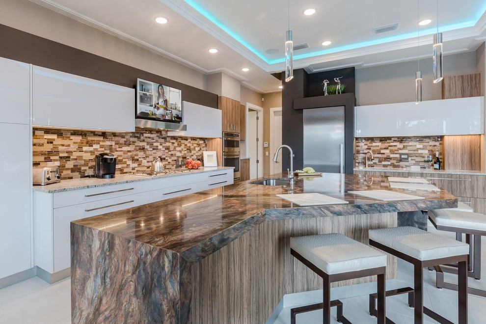 Contemporary kitchen in Miami with an undermount sink, flat-panel cabinets, white cabinets, multi-coloured splashback, matchstick tile splashback, stainless steel appliances, with island and white floor.