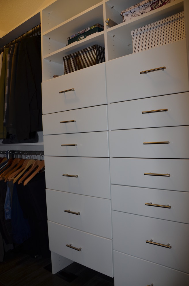This is an example of a mid-sized transitional walk-in wardrobe in Other with flat-panel cabinets, white cabinets and vinyl floors.