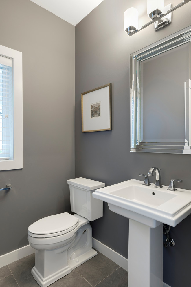 Design ideas for a mid-sized transitional powder room in Other with a two-piece toilet, grey walls, a pedestal sink and grey floor.