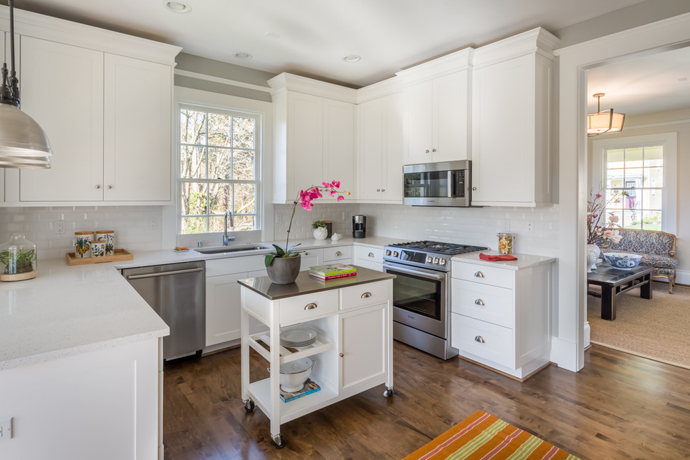 Inspiration for a mid-sized transitional u-shaped eat-in kitchen in Seattle with an undermount sink, shaker cabinets, white cabinets, quartz benchtops, white splashback, ceramic splashback, stainless steel appliances, medium hardwood floors and a peninsula.