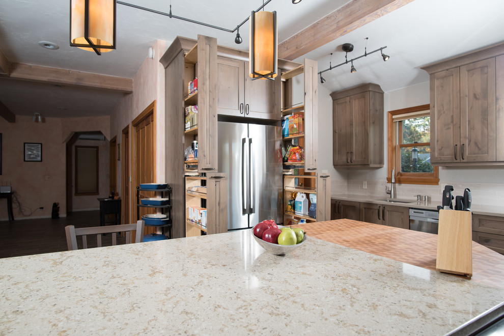 Example of a mid-sized mountain style l-shaped porcelain tile, brown floor and exposed beam open concept kitchen design in Seattle with an undermount sink, recessed-panel cabinets, gray cabinets, quartz countertops, beige backsplash, ceramic backsplash, stainless steel appliances, an island and beige countertops
