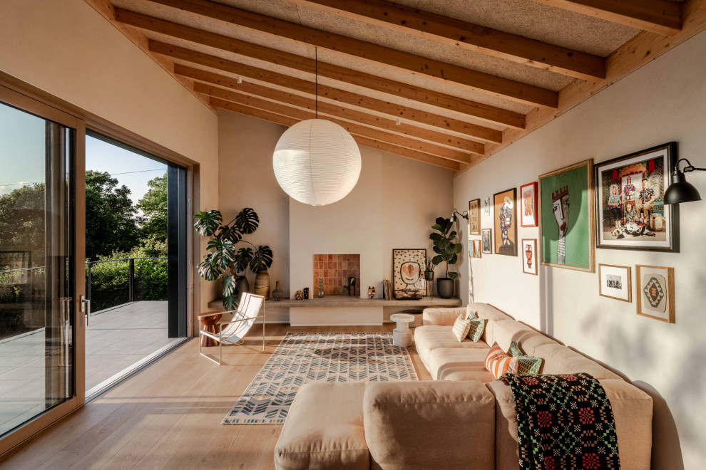 Design ideas for a contemporary living room in Other with beige walls, light hardwood flooring, a standard fireplace, beige floors, exposed beams and a vaulted ceiling.