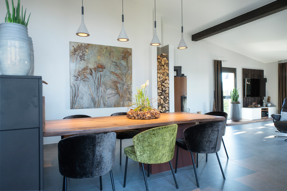 Photo of a large contemporary open plan dining in Nuremberg with white walls, concrete floors, a wood stove, a metal fireplace surround and grey floor.