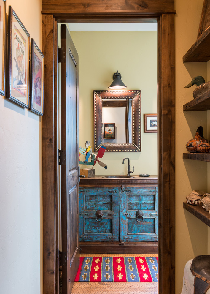 Powder room in Other with distressed cabinets, medium hardwood floors, a drop-in sink, wood benchtops and brown benchtops.
