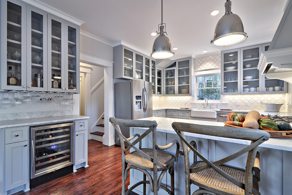 Photo of a large traditional kitchen in Austin with a farmhouse sink, shaker cabinets, grey cabinets, marble benchtops, white splashback, stainless steel appliances, dark hardwood floors and a peninsula.