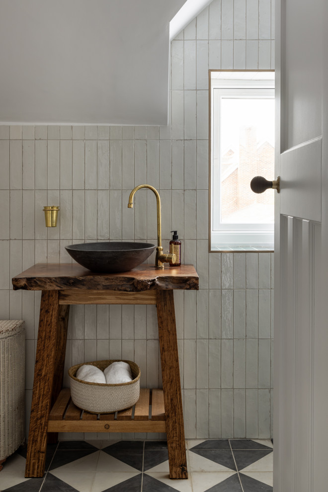 Photo of a traditional cloakroom in Oxfordshire with brown cabinets, white tiles, white walls, a vessel sink, wooden worktops, multi-coloured floors, brown worktops and a freestanding vanity unit.